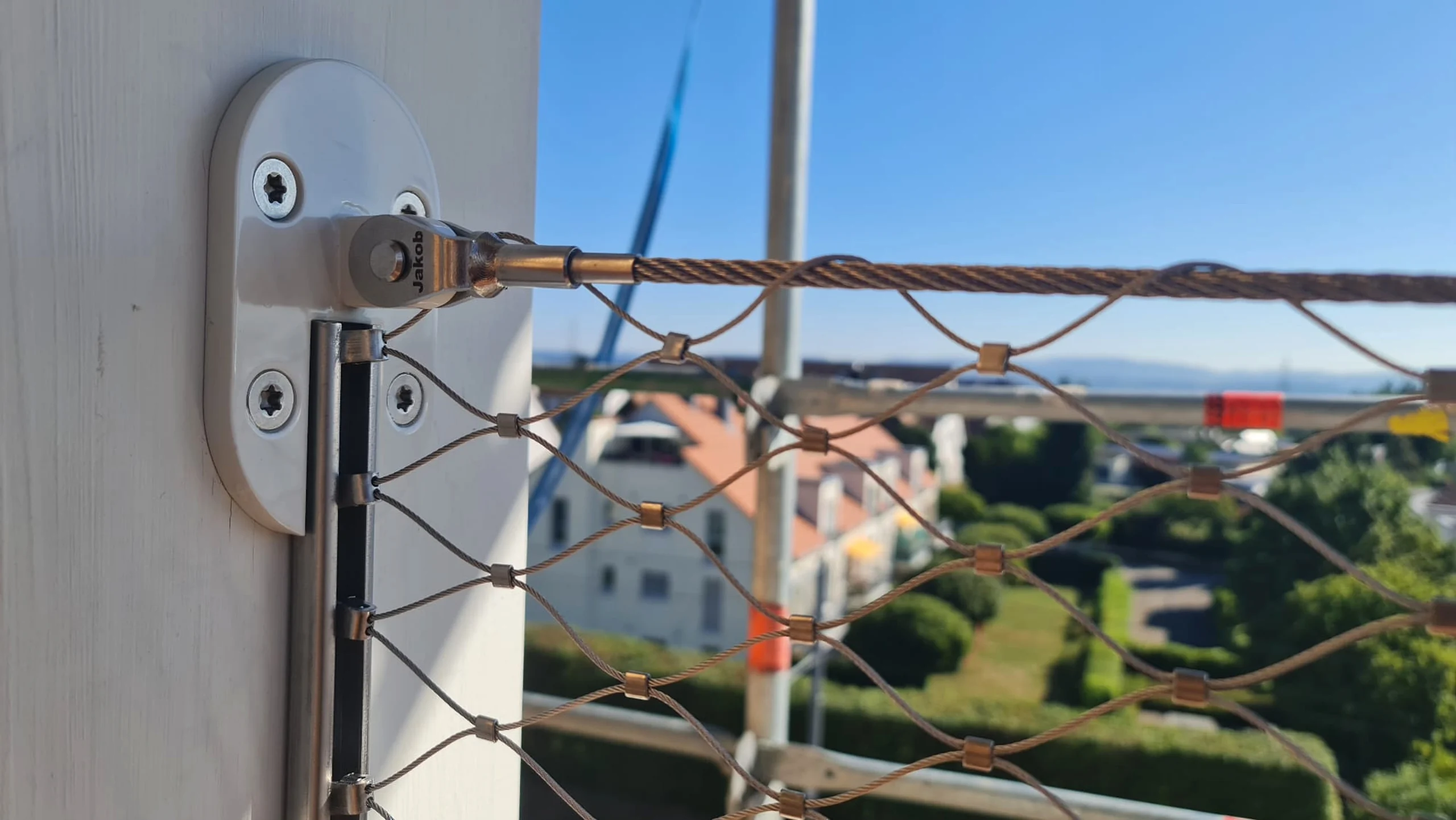 Detail: Edelstahl-Beschlag und gespanntes Seilnetz mit Blick über den Ort